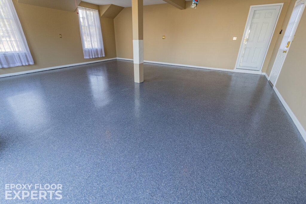 Dolerite flake epoxy is a blend of neutral and cool-toned stone flakes. Flake is a durable and easy-to-maintain option for a garage. Epoxy is resistant to chemicals and can tolerate the pressure and use of a vehicle.